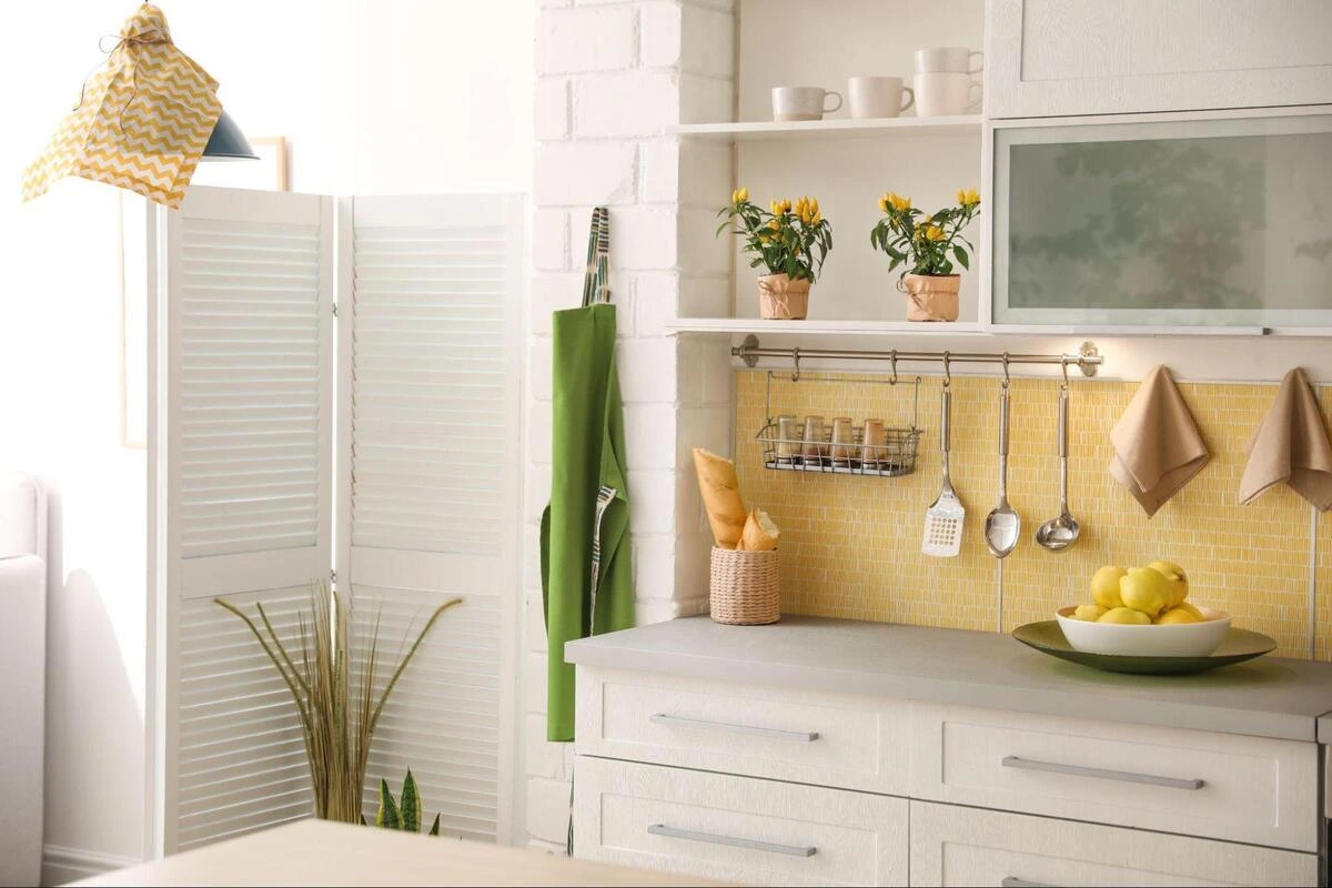 House Feng Shui Consultation - Modern Kitchen Layout and Element Balancing Bright contemporary kitchen interior featuring a yellow tiled backsplash, clean white cabinetry, fresh lemons, and green accent plants, strategically optimized during a comprehensive house feng shui consultation to balance the five elements and support the family wealth treasury sector.